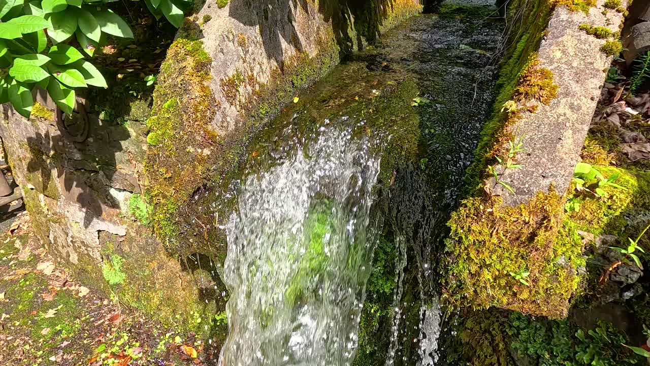 agua que fluye sobre la estructura de piedra de musgo