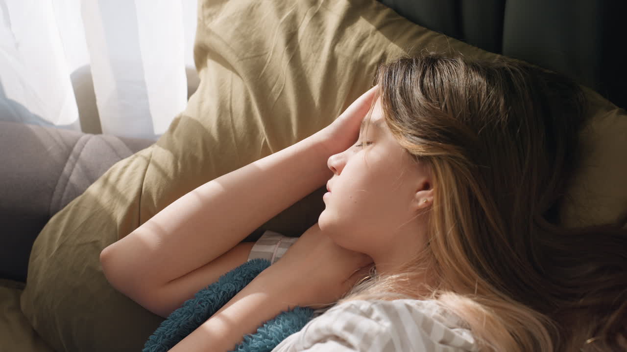 Gentle Rest Amid Soothing Surroundings, Tranquil Person Reclining Beneath Calming Teal Blanket During Quiet Daytime, Relaxed Figure Lying Peacefully With Soft Pillow And Sunlight Filling Room