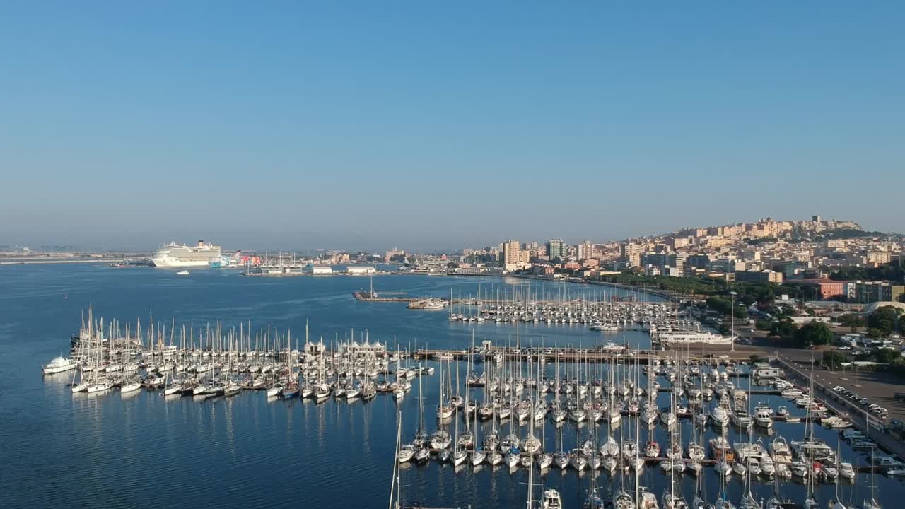 Drone shot showing marina full of yachts and boats beside coastal cityscape with cruise ship docked in clear blue sea at Split Croatia on sunny day
