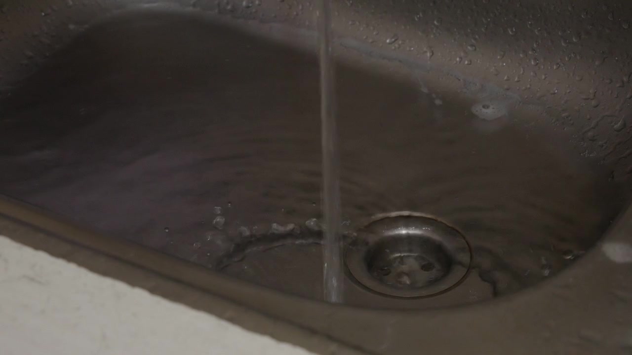 Eau de vaisselle sale s'écoulant dans un siphon d'évier de cuisine