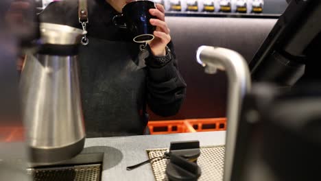 barista pours coffee and takes a sip