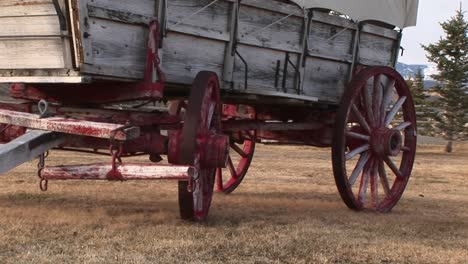 a close look at the lower half of a covered wagon with its wagon wheels painted red