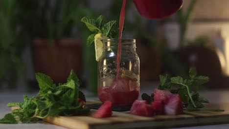 a fresh delicious watermelon juice smoothie poured into a glass mason jar with ice, mint and lemon