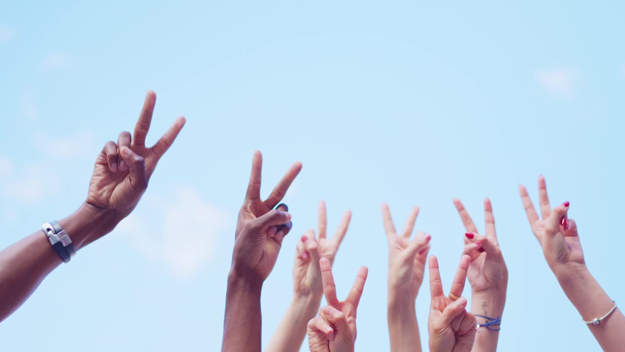 Diverse Hands Raising Peace Signs Against a Blue Sky