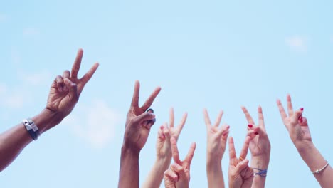 diverse hands raising peace signs against a blue sky