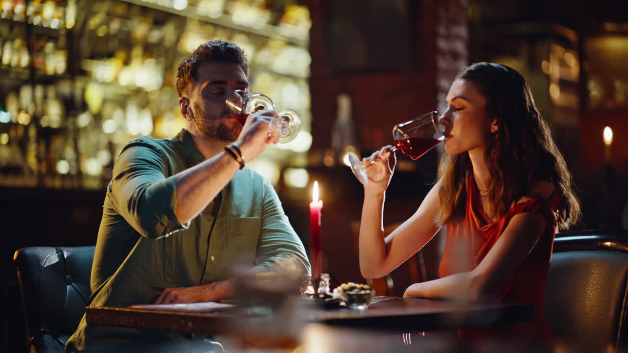 Primi piani di due innamorati che fanno tintinnare i calici all'interno di un ristorante di lusso