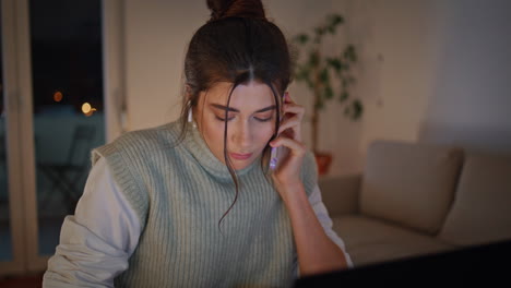 busy businesswoman answering cellphone call working at evening workplace closeup