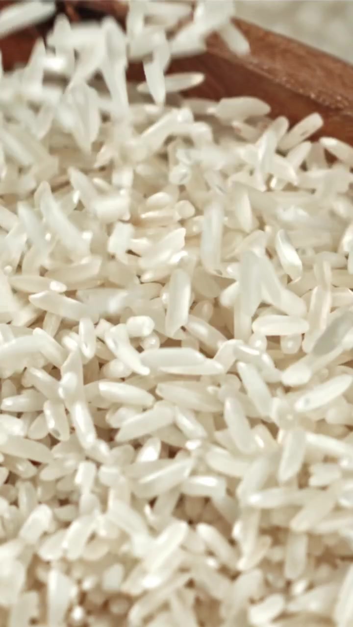 Chicchi di riso bianco crudo che cadono al rallentatore