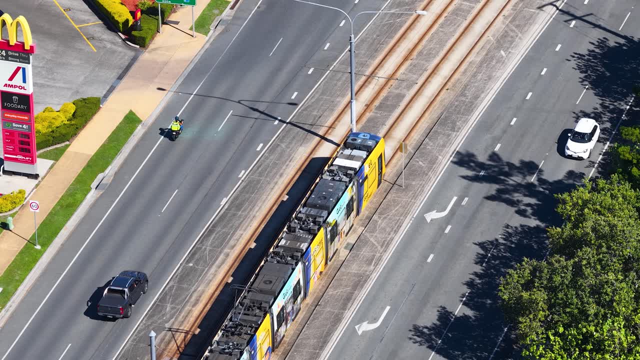 Yoğun şehir yollarının kenarındaki raylarda ilerleyen modern bir tramvayın yüksek açılı hava çekimi.
