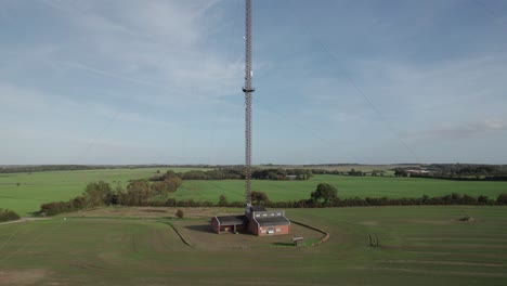 zoom out aerial view communication antenna, tv and radio tower on field in denmark - dolly shot