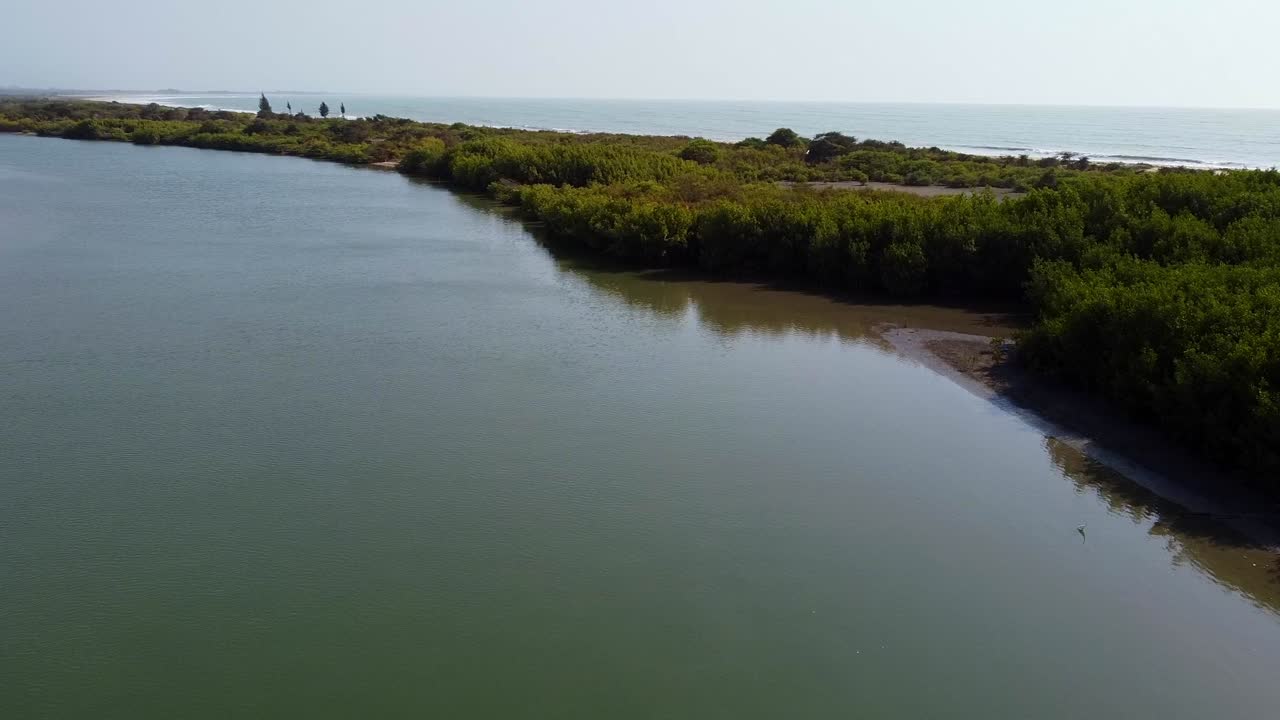 Vista aérea cinematográfica voando sobre o Rio Gâmbia para revelar o Oceano Atlântico.