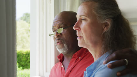 happy senior diverse couple wearing shirts and embracing in living room