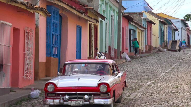 A beautiful shot of the buildings and cobblestone streets of Trinidad Cuba with old classic car passing 1