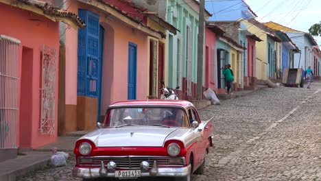 una hermosa foto de los edificios y calles empedradas de trinidad cuba con un viejo auto clásico pasando 1