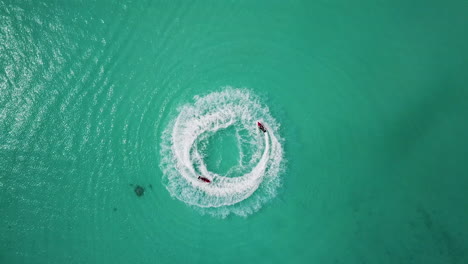 rising drone shot of couples jet sking in the turquoise waters near the maldives