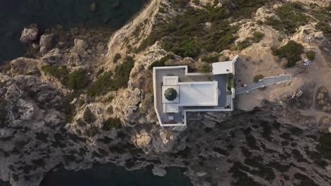 Una-Vista-Aérea-De-Pájaro-De-Un-Faro-En-El-Borde-De-Algunos-Acantilados-Junto-Al-Mar