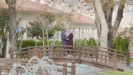 couple walking on a bridge in a park