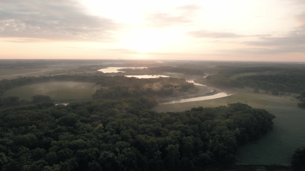 Sunrise creates dramatic light and long shadows across fields and rolling Midwestern terrain.