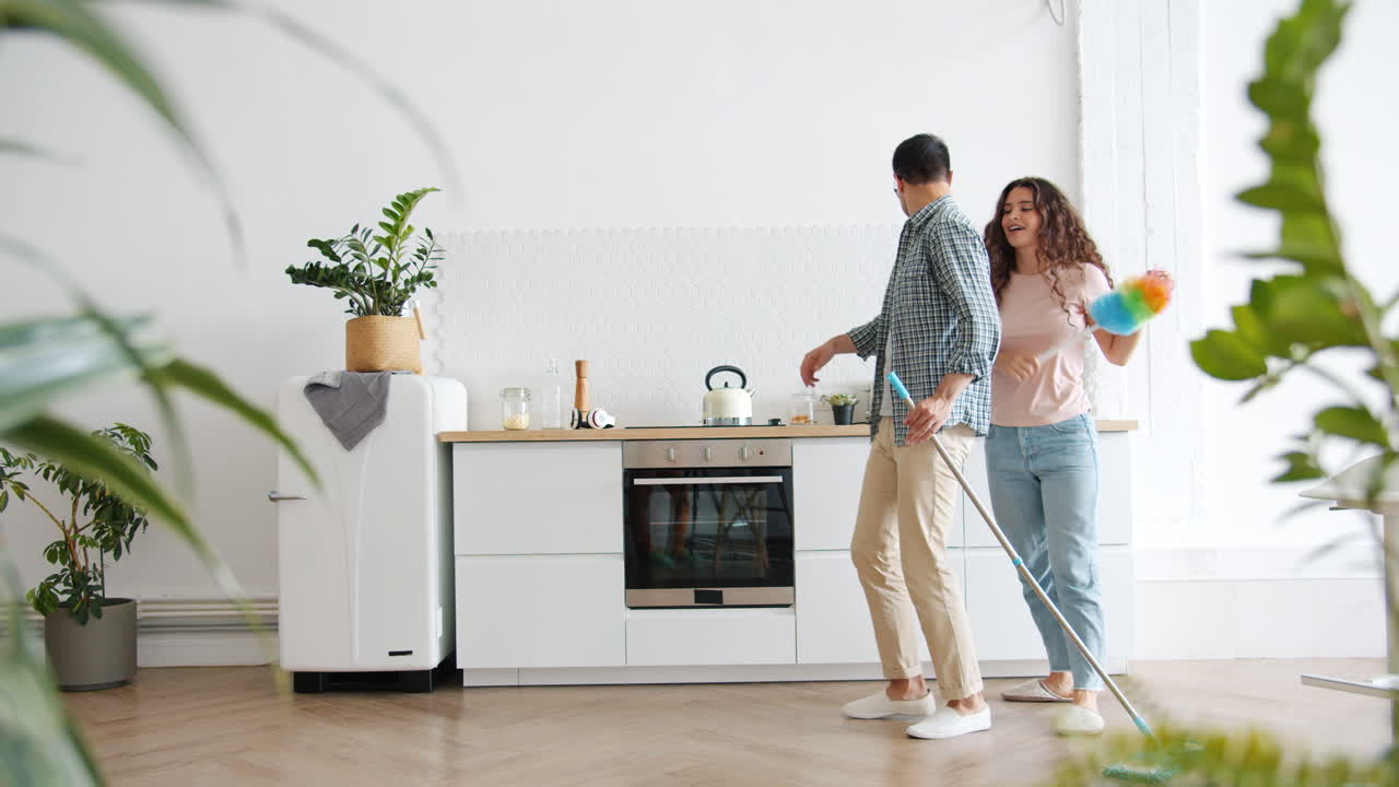 Couple Dancing While Cleaning Kitchen