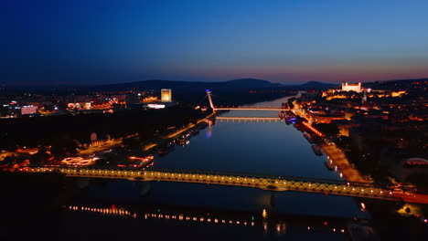 lights are on at the old bridge and ufo bridge over the danube. night view of bratislava, slovakia at night. aerial view