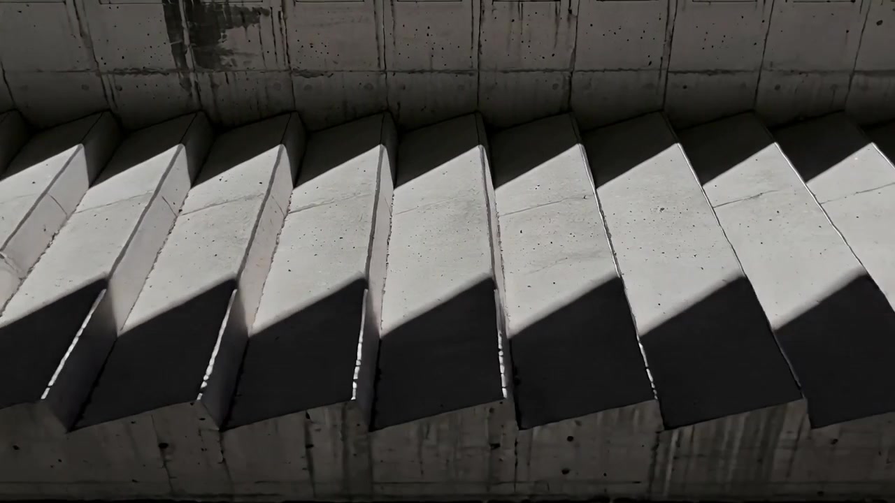 Sun drifting, casting light across concrete fins under slab, revealing triangular light and shadows