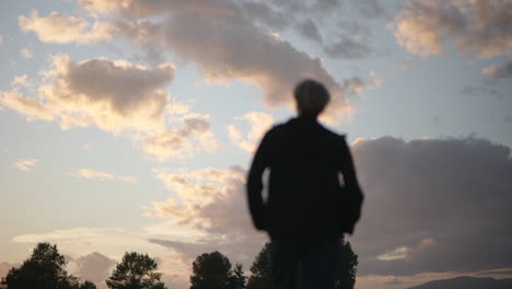 low angle view of silhouetted person looking up at sunset or sunrise sky