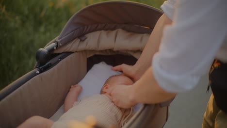 young mother with baby stroller at sunset