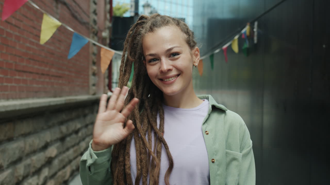 Woman with Dreadlocks Waving in an Urban Alley