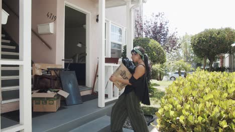 woman walking with a box of stuff moving into a new house