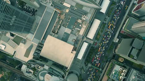 Cinematic-urban-drone-footage-of-an-aerial-smoky-view-flying-over-skyscrapers-and-boulevards-in-the-middle-of-downtown-Bangkok,-Thailand-during-burning-season-looking-down-from-a-bird's-point-of-view