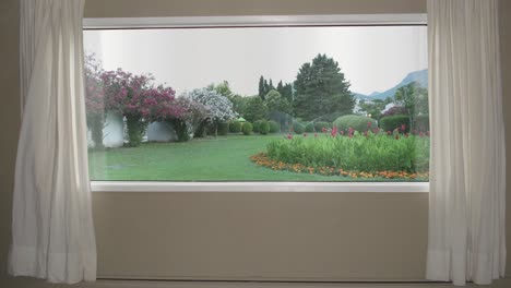 view from the window to beautiful garden with lawn, flowers and automatic sprinkler system. background plate, chroma key video background