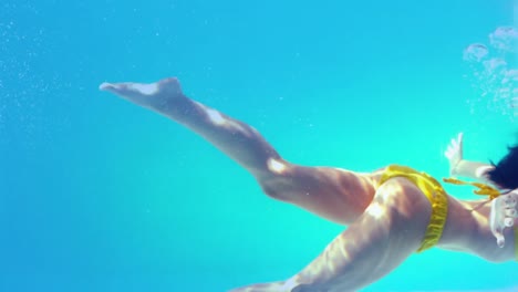 hermosa morena en bikini amarillo nadando bajo el agua