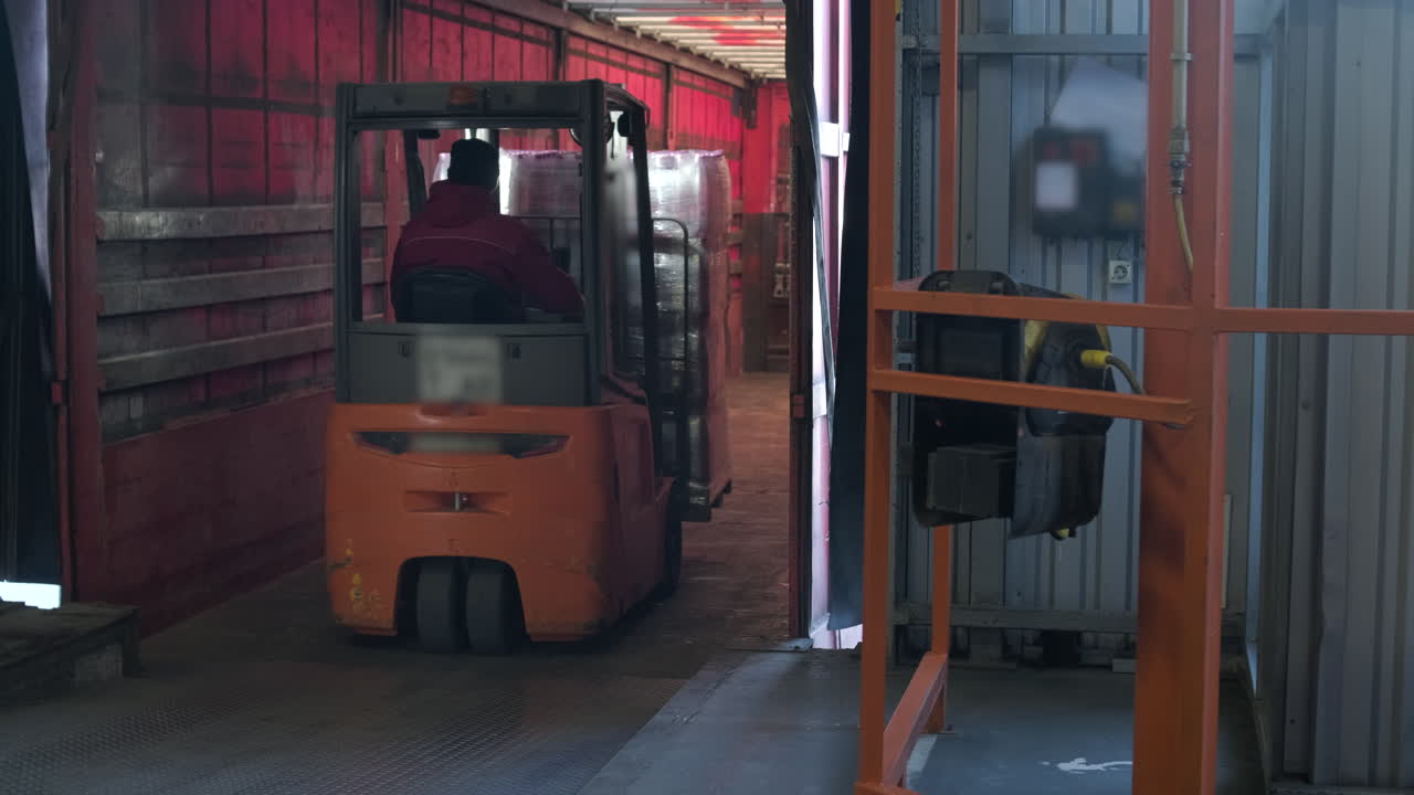 Carrello elevatore che carica pallet di merce in un camion in un magazzino.