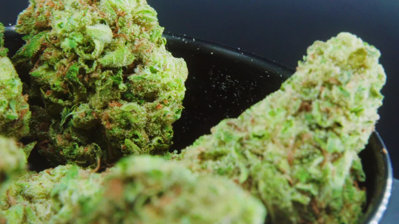 Macro Green Dried Marijuana Buds Close Up concept Shot, pile of dried marijuana plants, orange trichomes strains, in small black shiny bawl, on a rotating stand, studio lights, slow motion, 4K video