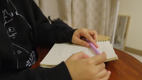 Close-up-shot-of-hands-tapping-to-a-beat-while-thinking-on-top-of-notebook,-pen,-and-guitar