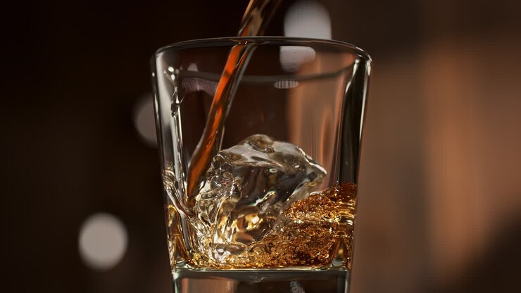 Whisky Pouring Over Ice Cubes And Swirling In The Glass, Warm Wooden Background