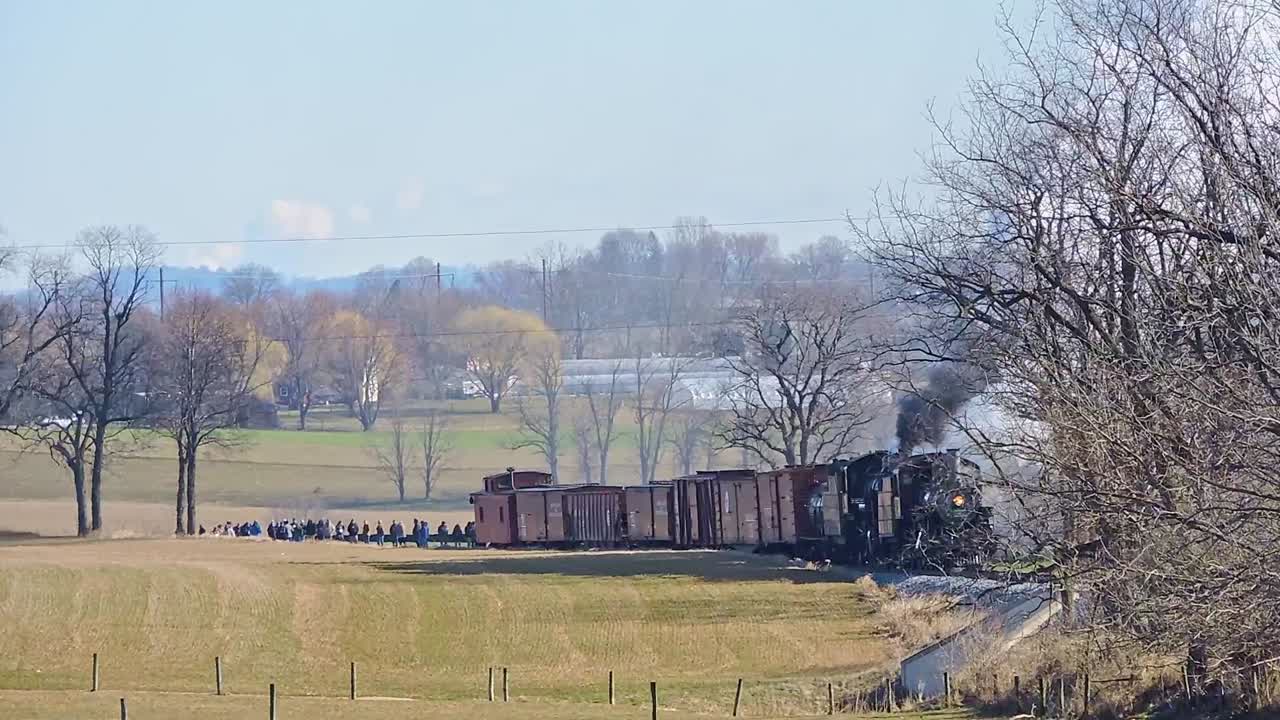 A Group of People Gather to Witness a Large Double Header Train Smoke Incident in a Rural Area