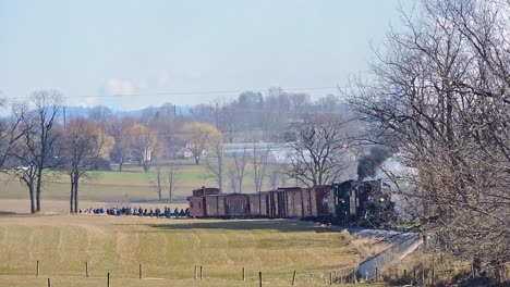 a group of people gather to witness a large double header train smoke incident in a rural area