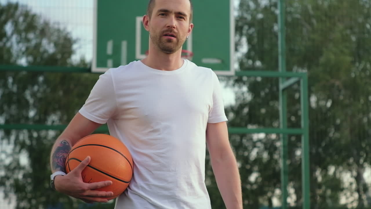 hombre sosteniendo una pelota de baloncesto en una cancha