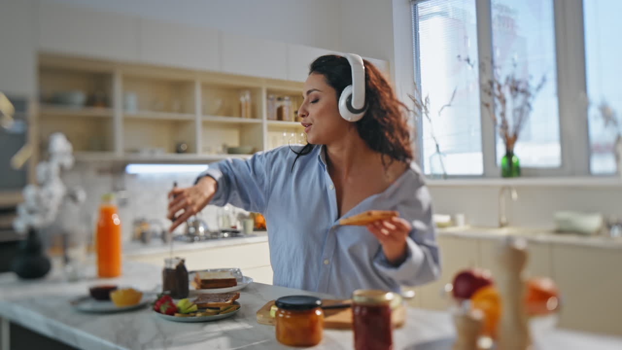 chica preparando comida auriculares cantando una canción en la cocina. mujer bailando cocinando