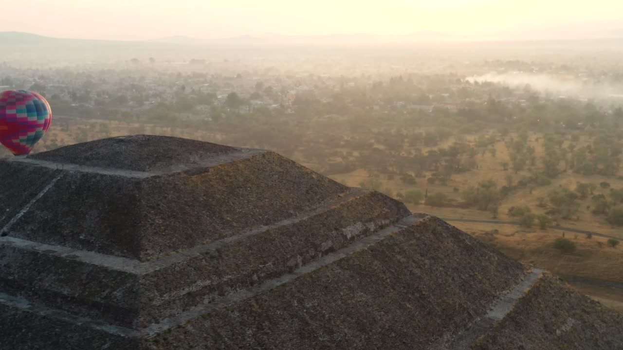 일출 동안 멕시코 테오티후칸에 있는 아즈텍 문화의 피라미드로 날아가는 열기구의 공중 전망, 4k