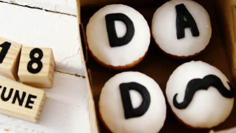 cupcakes with text dad in a box on wooden plank 4k