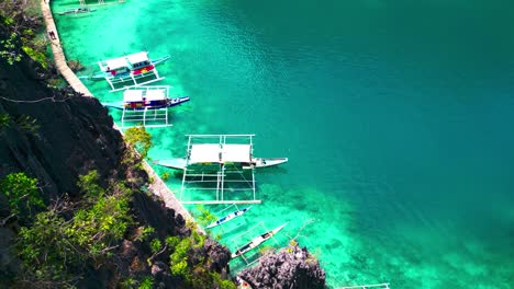 Kayangan-Lake-Aerial-Ascend-Above-Tour-Boats-Docked-Next-To-Mountain