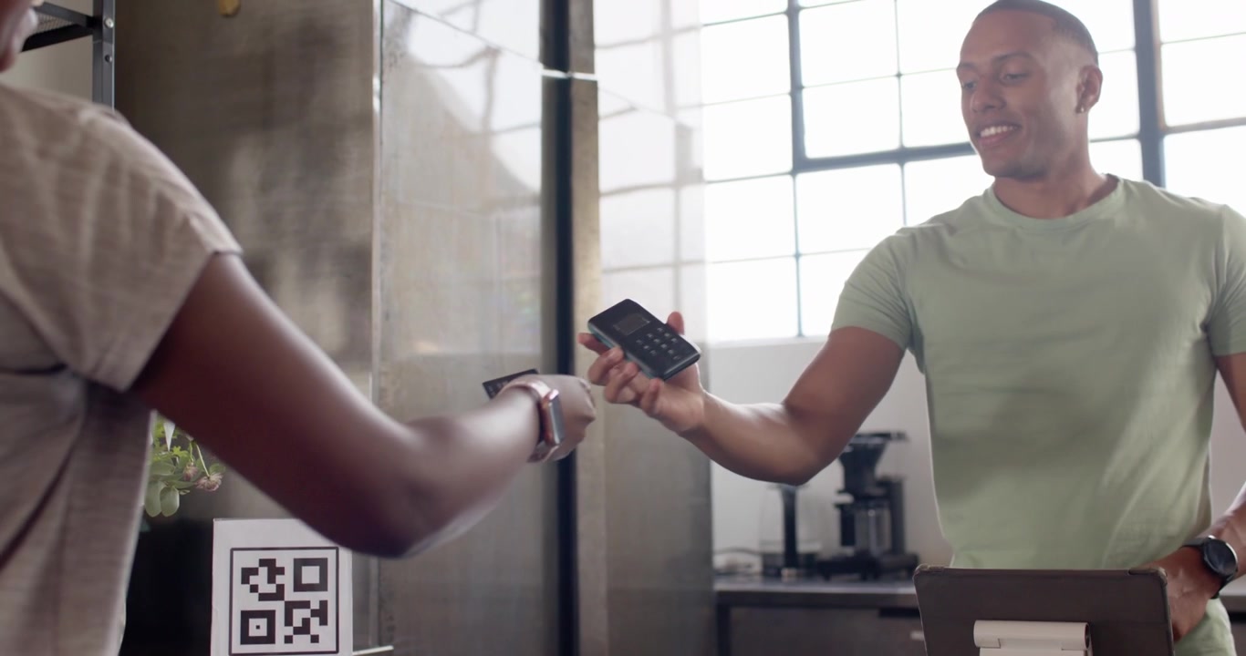 Male cashier taking phone at cafe after client holding watch using tablet closing sale, copy space