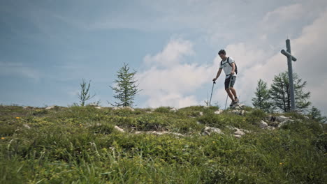 young hiker with hiking poles walking at the top of the ridge, camera shot with a low perspective, past the wooden bech with a carved heart in the middle