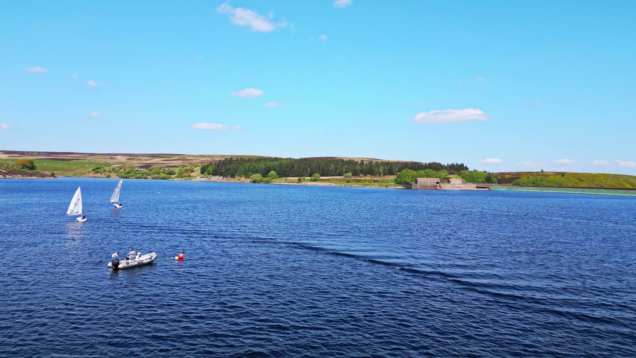 el embalse de winscar, un pintoresco lago azul en yorkshire, donde los barcos de vela con velas blancas se deslizan con gracia a través de las aguas tranquilas