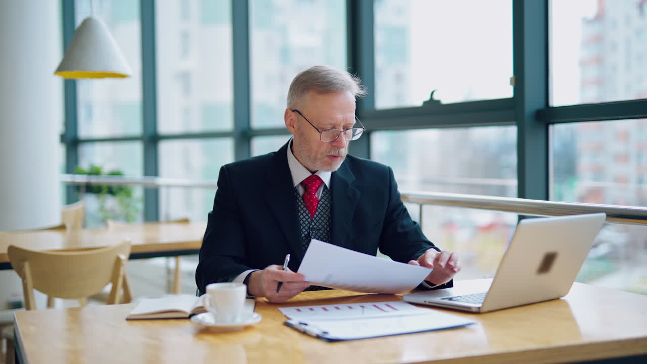 Serious senior businessman in cafe. Businessman working on business project in city cafe