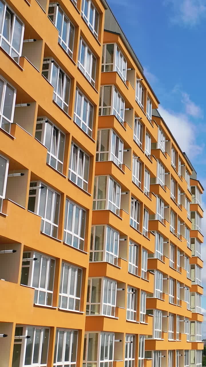Cropped view of the modern apartment buildings exteriors. Contemporary residential orange and white buildings with outdoor facilities Vertical video