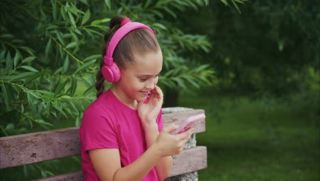 a young girl enjoying a joyful moment while listening to music with headphones, engaged with her phone in a lush green outdoor setting