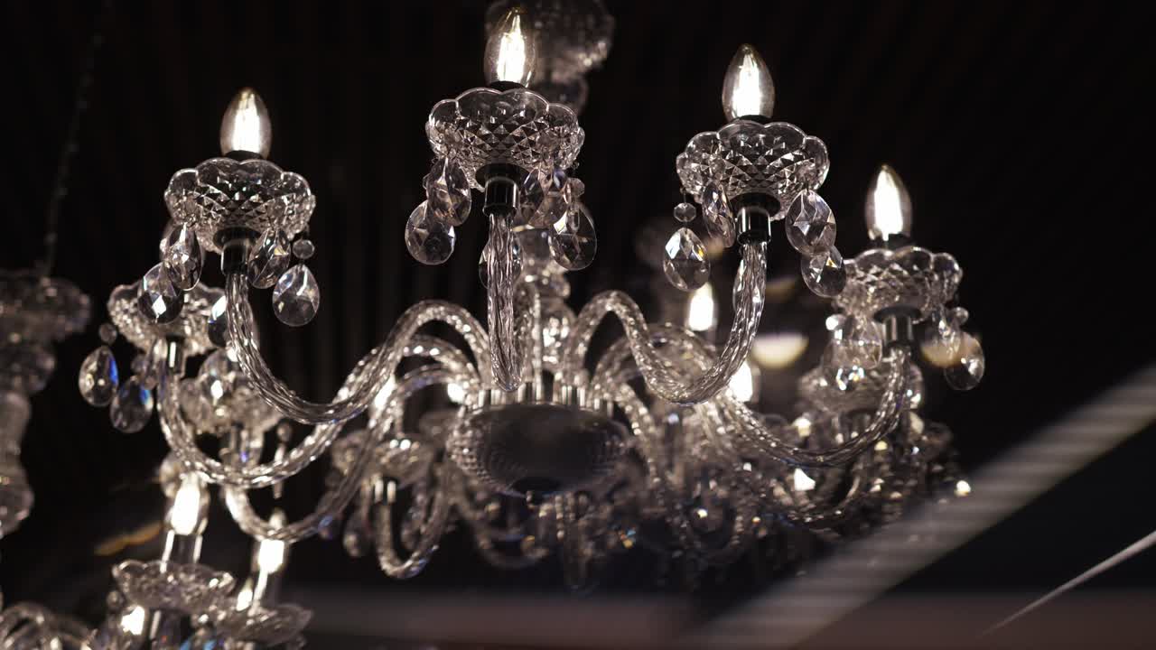 luxurious crystal chandelier lit with warm bulbs reflecting sparkling light in dark space